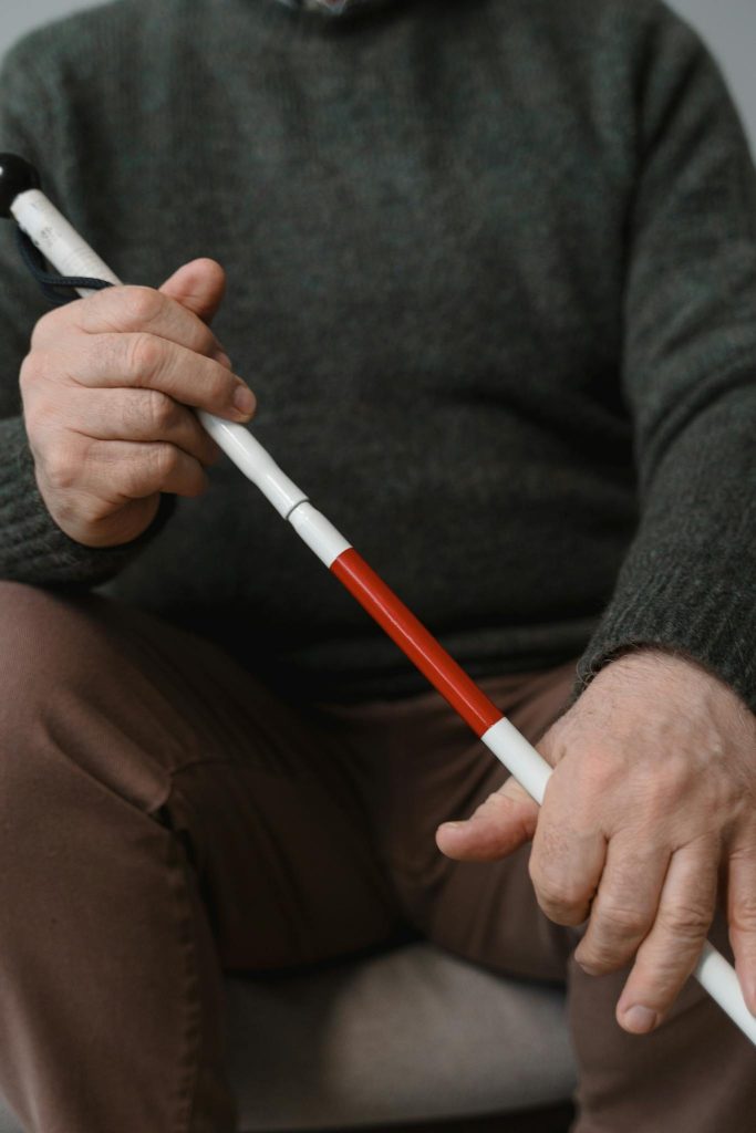 Cropped view of a person holding a white cane, symbolizing mobility and independence for visually impaired individuals.