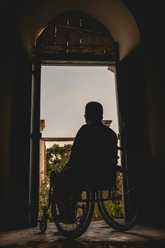 pexels-photo-3057504-3057504 Silhouette of a man in a wheelchair gazing outdoors, symbolizing solitude and reflection.
